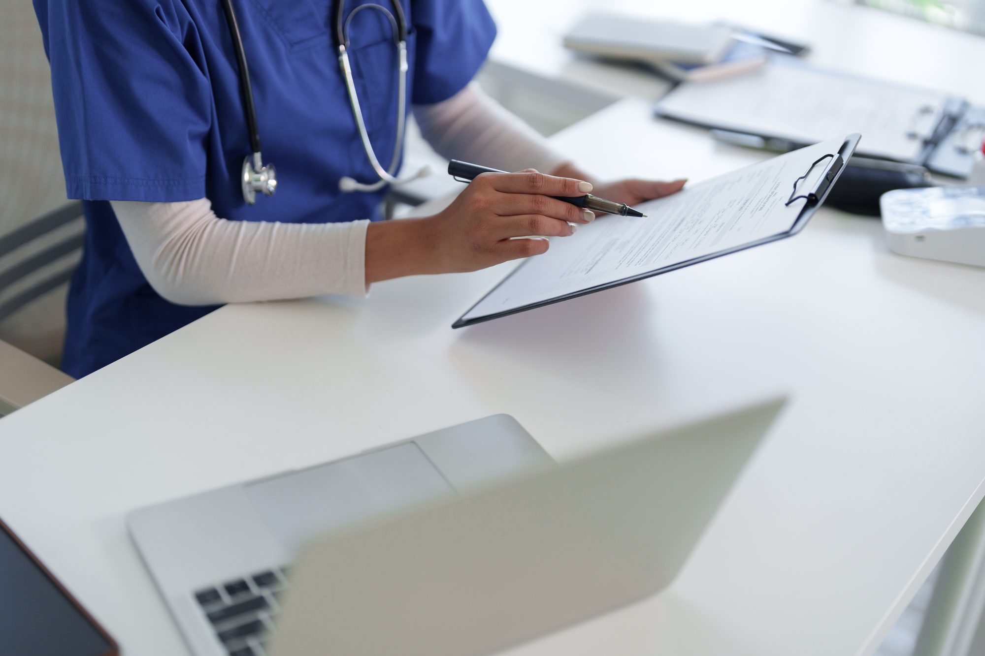 A healthcare administrator recording patient information at a desk