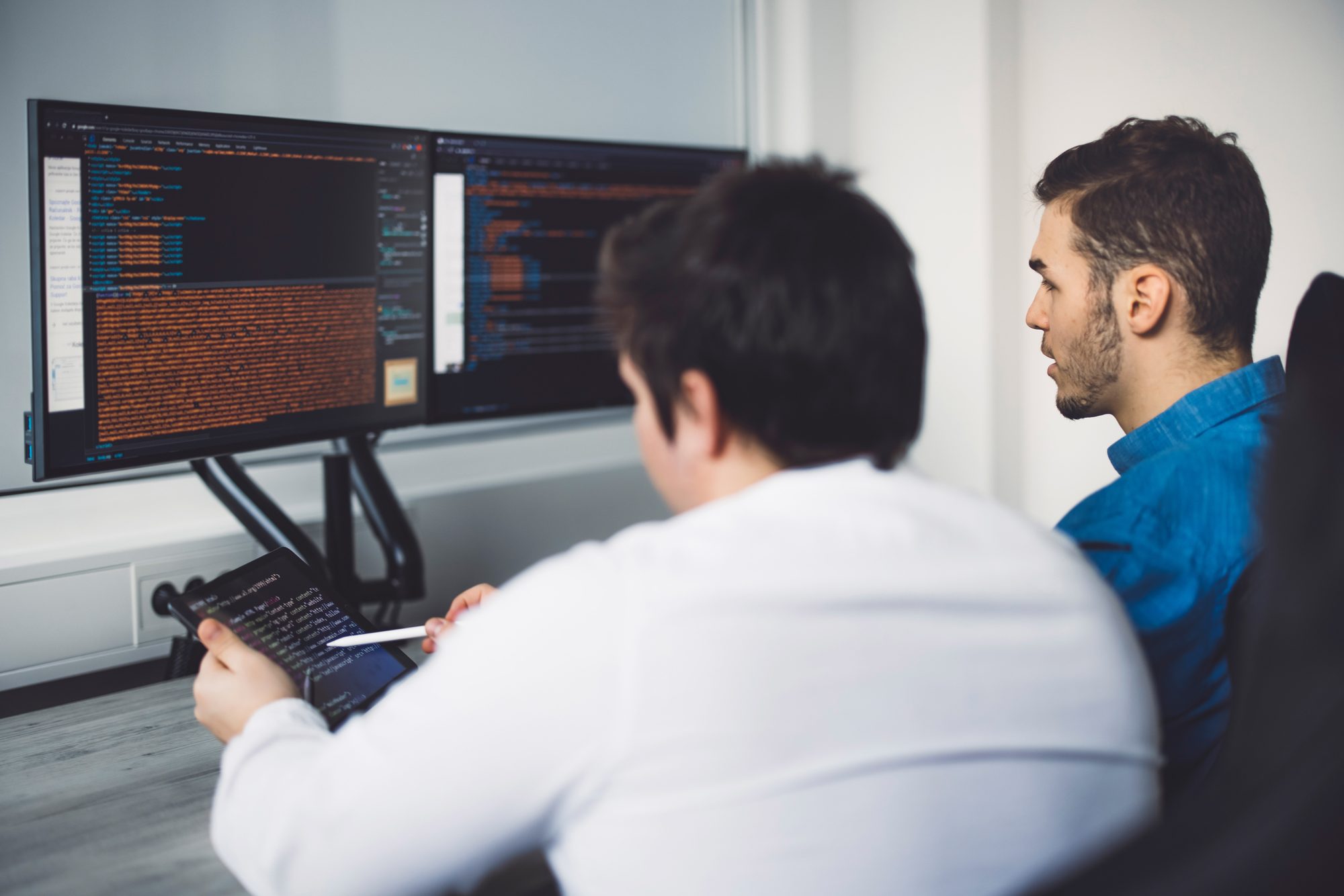 Two colleagues reviewing output on a monitor together