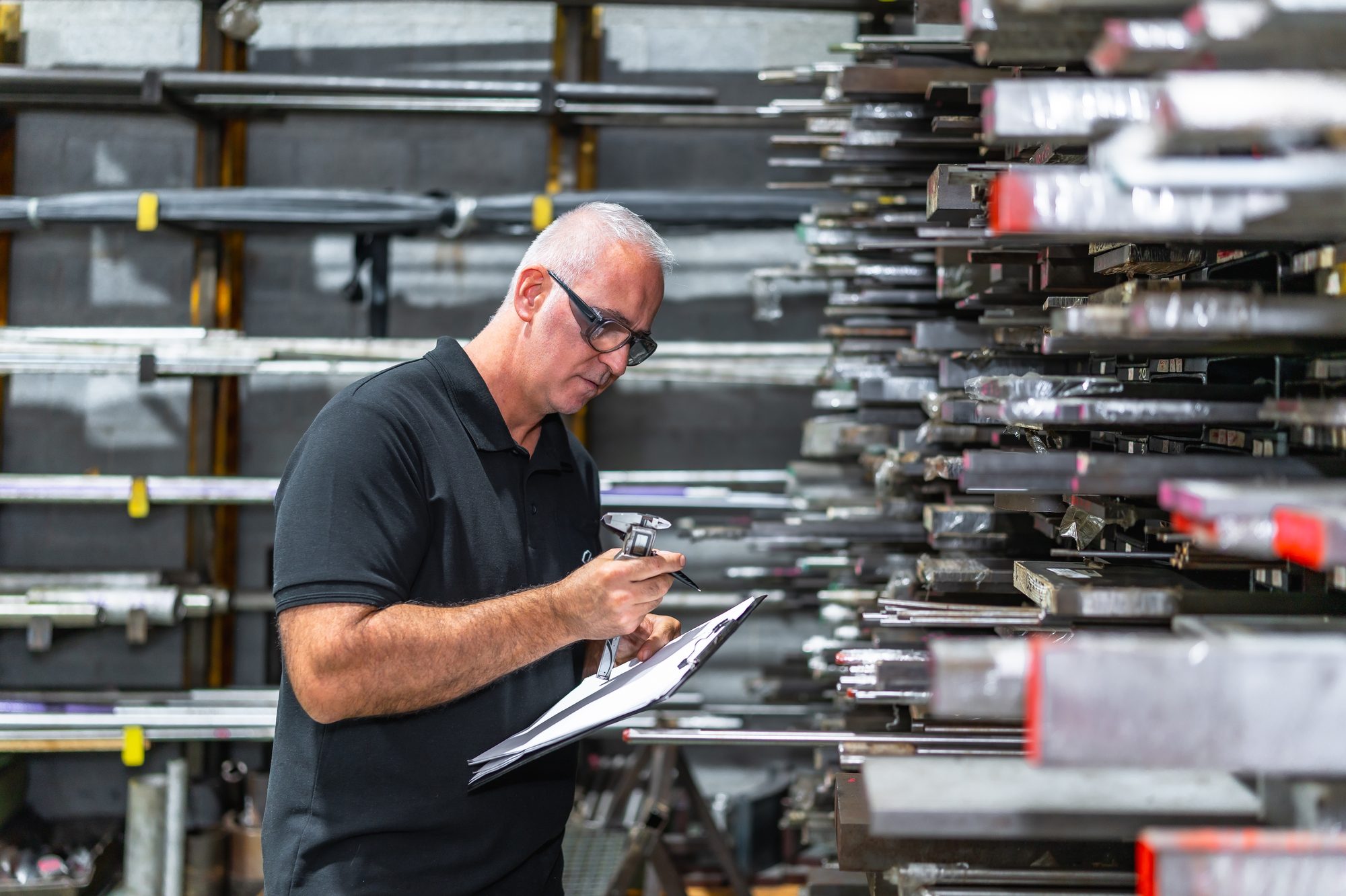 An inspector recording measurements on a clipboard in a workshop