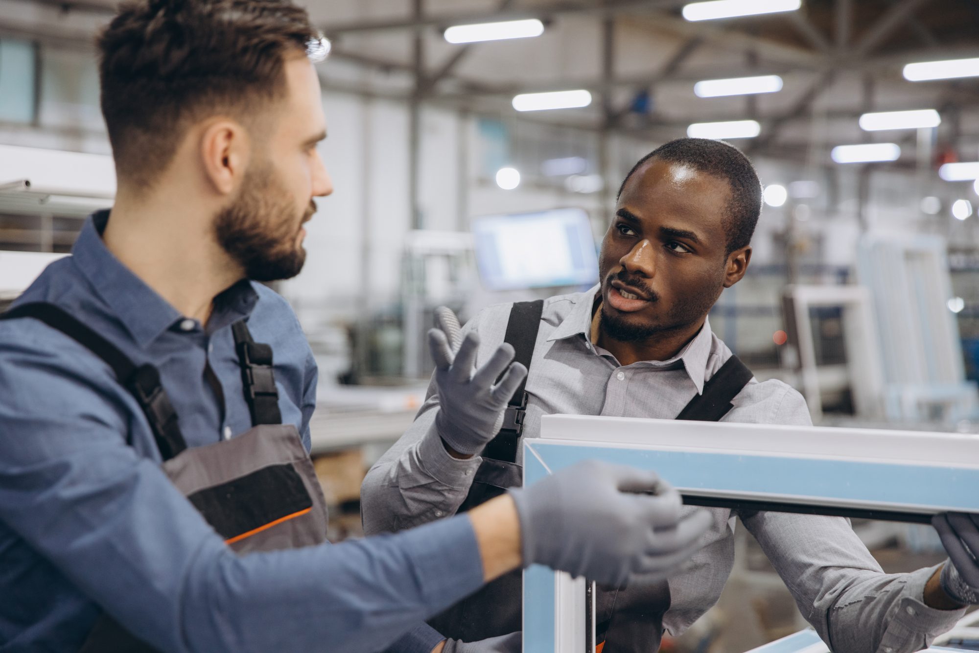 Two workers examining a manufactured component together